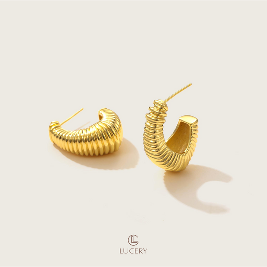 The Sculptural Ribbed Hoop Earrings make a bold statement with their stacked design, offering a contemporary twist on the classic hoop. Their sculpted appearance adds depth and character to any look.