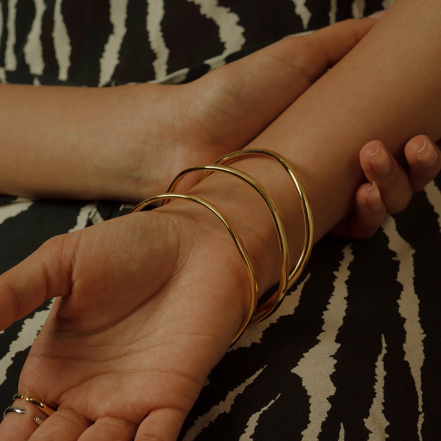 Elevate your wristwear with this trio of 18K gold-plated S925 silver bangles. Their intertwined design creates a dance of light and shadow, perfect for a touch of everyday elegance. Slim yet striking, they're an effortless statement piece.