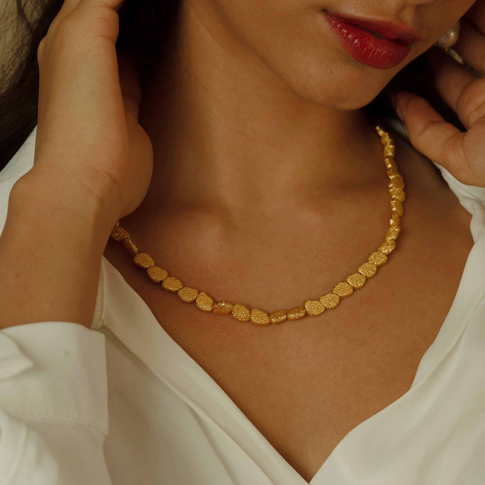 This necklace is a masterpiece of texture, with each gold element crafted to create a rich tapestry of light and shadow, wrapping the neck in a display of classical luxury.